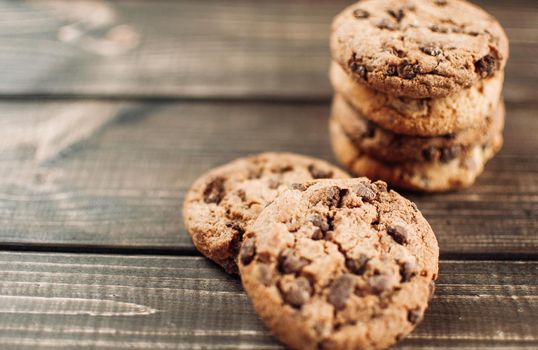 A stack of chocolate chip cookies lies on a wooden table. Rustic table. Vintage toning. Dietary useful cookies without gluten. Copy space.