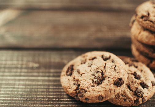 A stack of chocolate chip cookies lies on a wooden table. Rustic table. Vintage toning. Dietary useful cookies without gluten. Copy space.