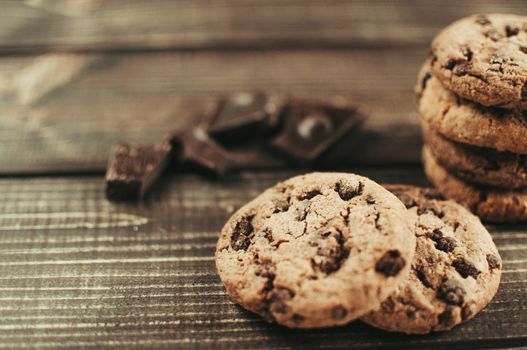 A stack of oatmeal cookies with chocolate pieces is lying on a wooden table. Rustic table. Vintage toning. Dietary useful cookies without gluten. Copy space.