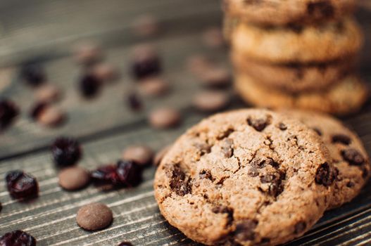 A stack of oatmeal cookies with chocolate pieces and candied fruits lies on a wooden table. Rustic table. Vintage toning. Dietary useful cookies without gluten. Copy space.