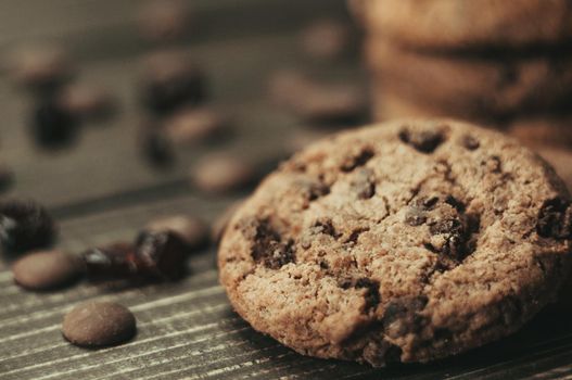 A stack of oatmeal cookies with chocolate pieces and candied fruits lies on a wooden table. Rustic table. Vintage toning. Dietary useful cookies without gluten. Copy space.