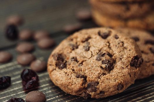 A stack of oatmeal cookies with chocolate pieces and candied fruits lies on a wooden table. Rustic table. Vintage toning. Dietary useful cookies without gluten. Copy space.