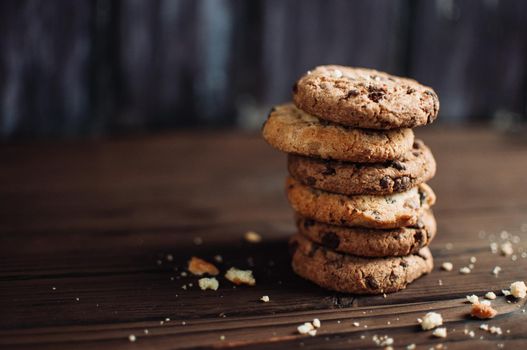 Cookies with chocolate worth a stack on a wooden table in a rustic style. Crumbs from biscuits on wooden boards. Selective focus