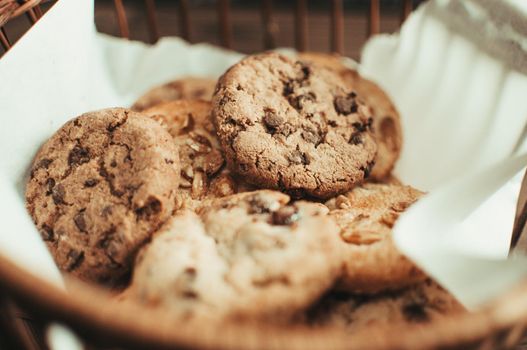 Cookies with chocolate lies in a wicker basket. A basket with gluten free cookies on a wooden table. Selective focus.