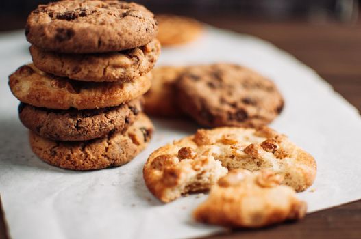 Chocolate cookies on parchment paper. Broken biscuits on a wooden table. Selective focus.