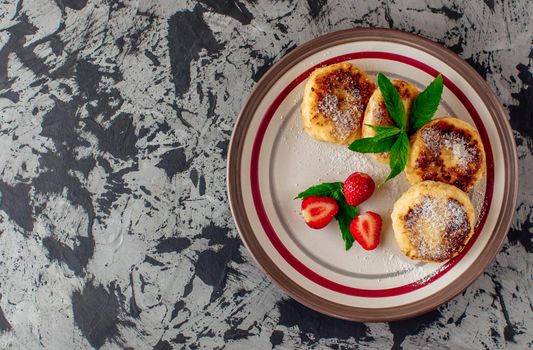 Gourmet breakfast - curd pancakes, cheesecakes, curd pancakes with strawberries, mint and icing sugar in a white plate. Selective focus. Top view. Copy space.