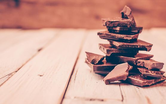 dark chocolate without sugar and gluten free for diabetics and allergics. Broken black chocolate pieces in a pile on a white table in a rustic style. Christmas tree made of chocolate pieces.