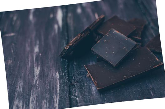 dark chocolate without sugar and gluten free for diabetics and allergics. Pieces of chocolate on a dark rustic table. Photo in a white frame at an angle. Copy space