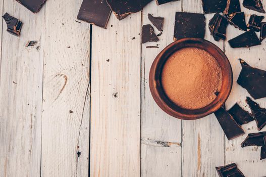 dark chocolate without sugar and gluten free for diabetics and allergics. Pieces of chocolate with crumbs and cocoa powder in the bowl on the right. Concept of healthy eating and diet. Copy space.