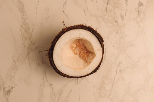ugly organic broken rotten coconut on a marble background. a broken nut in a shell the white insides of a coconut, which began to decompose and covered with fungus and mold.