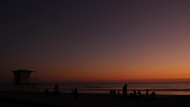 Oceanside, California USA - 8 Feb 2020: Silhouette of people making bbq campfire. Beachfront recreation area for barbeque with fire place on pacific ocean coast. Bonfire for barbecue on sunset beach.