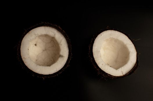 ugly organic coconut on a black background, isolate. a broken nut in a shell the white insides of a coconut, which began to decompose and covered with fungus and mold. Spoiled products.