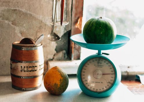 Autumn still life with melon and watermelon on a scale and on a wooden white table. Weighing the crop. Autumn harvest concept. Happy Thanksgiving. Selective focus. Horizontal orientation.