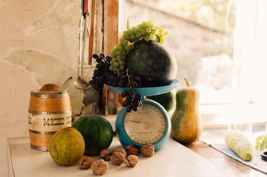 Autumn still life with pumpkins,walnuts,melons,watermelon and grapes on scale to scale and on a wooden white table. Autumn harvest concept. Happy Thanksgiving. Selective focus. Horizontal orientation.