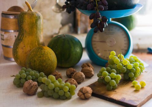 Autumn still life with pumpkins,walnuts,melons, watermelon and grapes on a scale to scale and on a wooden white table. Autumn harvest concept. Happy Thanksgiving. Selective focus. Template for design.