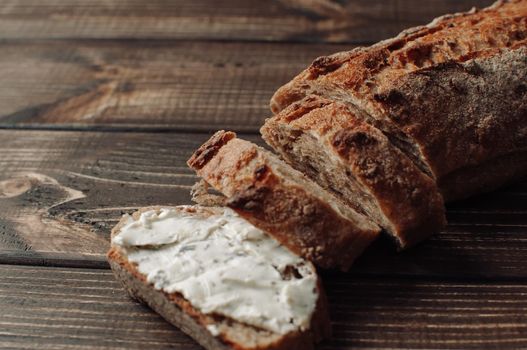 dark buckwheat bread with sisam plastered with cottage cheese with herbs in a cut on a wooden table in a rustic style. Snack and breakfast concept. Selective focus.