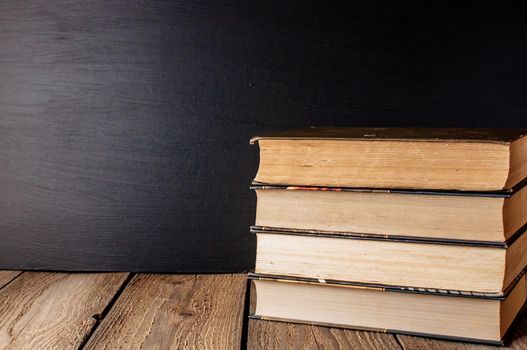 books stacked on a wooden table in a rustic style on the background a school blackboard. The concept of welcome back to school. copy space