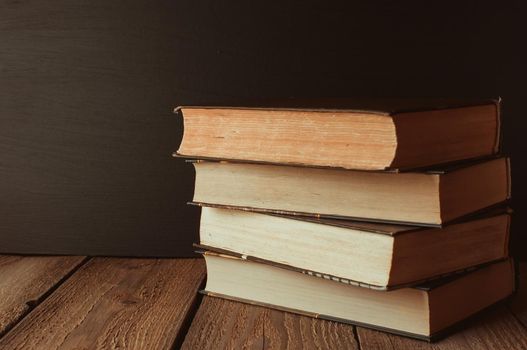 books stacked on a wooden table in a rustic style on the background a school blackboard. The concept of welcome back to school. copy space