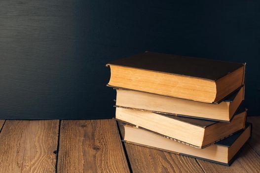 books stacked on a wooden table in a rustic style on the background a school blackboard. The concept of welcome back to school. copy space