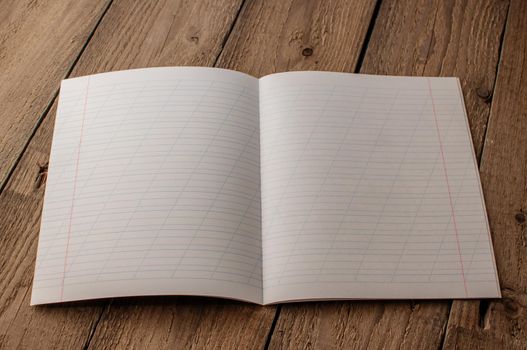 Back to school, the concept of raising children. Day of knowledge. Notebook in a slanting line on a wooden table with space for text. Save space. Rustic and vintage toning.