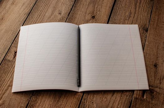 Back to school, the concept of raising children. Day of knowledge. Notebook in a slanting line on a wooden table with space for text. Save space. Rustic and vintage toning.