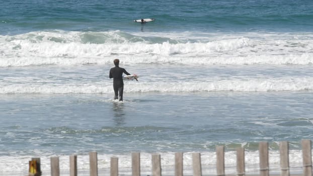 Encinitas, California USA - 23 Feb 2020: Surfers in ocean, pacific coast big blue sea water waves. People surfing, sport with surfboards. Healthy lifestyle, watersport hobby. Person and surf or tide.