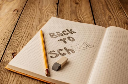 Back to school, the concept of raising children. Day of knowledge. Notebook in a slanting line on a wooden table with space for text. Save space. Rustic and vintage toning.