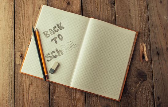 Back to school, the concept of raising children. Day of knowledge. Notebook in a slanting line on a wooden table with space for text. Save space. Rustic and vintage toning.