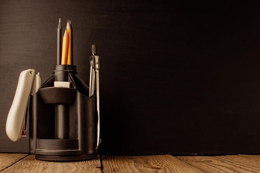 Back to school, the concept of parenting. An assortment of consumables, stands for pens and pencils, an eraser, stationery knives, compasses.Education concept.Copy space. Rustic and vintage toning.