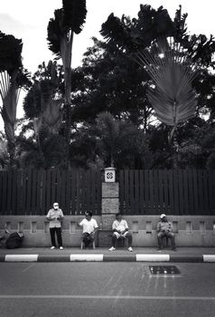 2019-11-05 / Phuket, Thailand - Four sitting men idling on the sidewalk. Black and white.