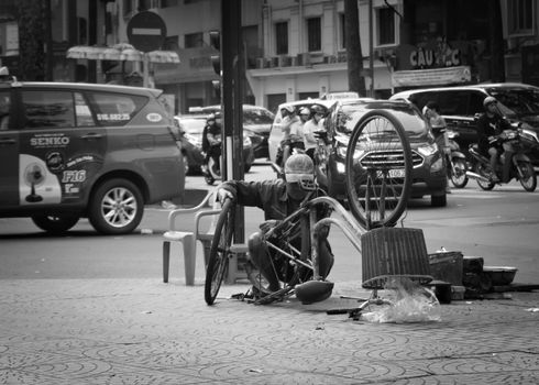2019-11-12 / Ho Chi Minh CIty, Vietnam - A man repairing an old bicyle on a sidewalk. Black and white.