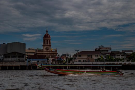 Bangkok, Thailand - 21 Jul 2019 : Long-tailed  boat rushing on water surface against of Chao Phraya  through the Santa Cruz Church in the Kingdom of Thailand.