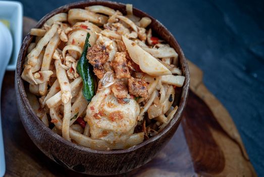 Thai food, Spicy stir fried bamboo shoot with fish ball in a wooden bowl. Oblique view from the top.