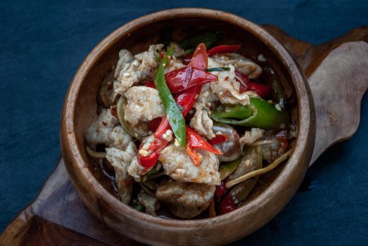Thai Spicy food, Spicy stir fried fish balls and thai herbs vegetables in wooden bowl : in Thai language called "Pad Cha " Oblique view from the top.