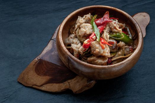 Thai Spicy food, Spicy stir fried fish balls and thai herbs vegetables in wooden bowl : in Thai language called "Pad Cha " Oblique view from the top.