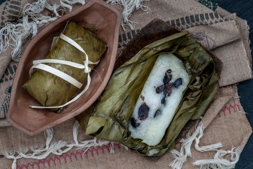 Khao tom mat, a Laotian and Thai dessert of seasoned steamed sticky rice wrapped in banana leaves normally inserted with filling made of banana and black beans for special occasions or merit making, Steamed mung bean with sticky rice. Top view.