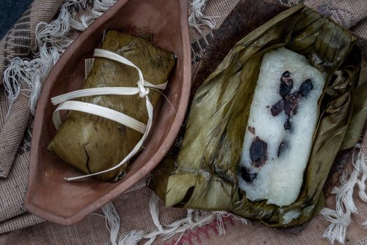 Khao tom mat, a Laotian and Thai dessert of seasoned steamed sticky rice wrapped in banana leaves normally inserted with filling made of banana and black beans for special occasions or merit making, Steamed mung bean with sticky rice. Top view.