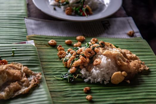 Rice topped with Stir fried Thai basil with dwarf prawn and Fried egg on served a banana leaf, A world renowned delicacy from Thailand, Selective focus.