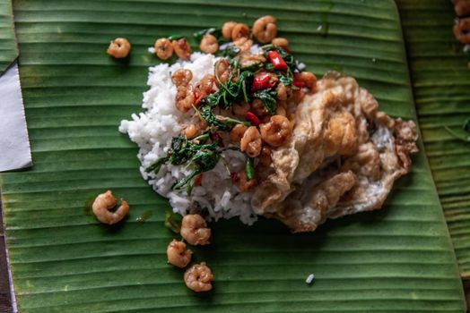 Rice topped with Stir fried Thai basil with dwarf prawn and Fried egg on served a banana leaf, A world renowned delicacy from Thailand, Selective focus.