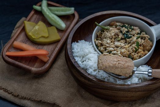 Thai food, The hand is using a fork to scoop Stir fried egg tofu with spring onion with Herbs vegetables served with steamed rice in wooden bowl.