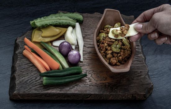 Thai food, The hand is using ginger to scoop Southern Thai dry curry with ground pork Khua Kling, Thai dry curry with ground pork with Herbs vegetables.