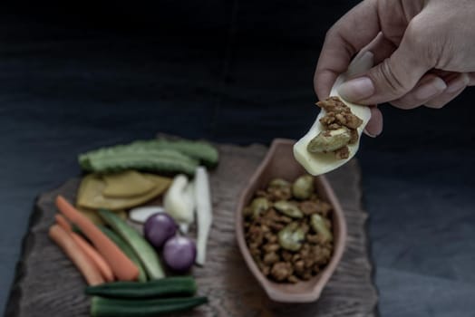 Thai food, The hand is using ginger to scoop Southern Thai dry curry with ground pork Khua Kling, Thai dry curry with ground pork with Herbs vegetables.