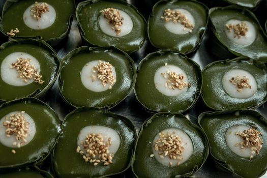 Thai Dessert Pandan Sweet Pudding (Kanom Piak Poon Bai Toey) in Sweet Coconut milk Cream with sesame seeds and Thai pudding with coconut topping, Thai dessert, Selective focus.