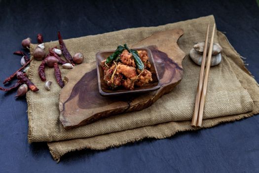 Thai Spicy food, Spicy Stir Fried Deep Fish Fillet with Herbs vegetables  in wooden bowl : in Thai language called "Pad Cha ". Oblique view from the top.
