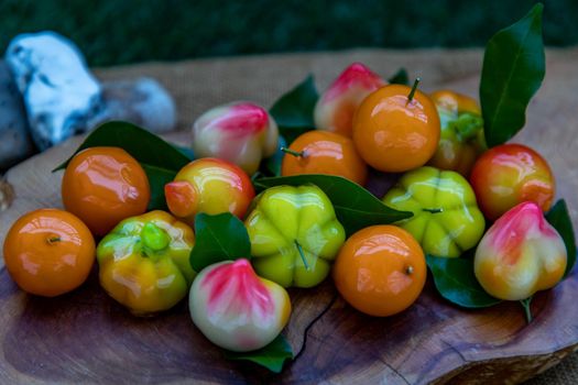 Close up of Kanom Look Choup : An old traditional thai dessert made from green been, coconut milk, sugar and jelly, Deletable imitation fruits made from green been, coconut milk, sugar and jelly in fruit shape on wooden, It is a unique dessert of Thailand.