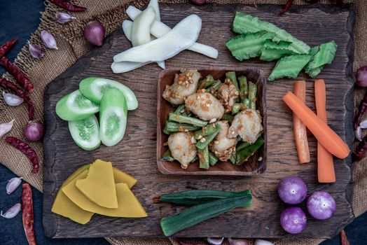 Thai food, Stir Fried fish ball with Red Curry Paste and long bean with the ingredient and fresh vegetables on wood background, view from above.