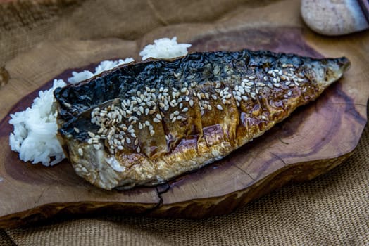 Japanese meal for dinner saba fish grilled on rice with teriyaki sauce on a wooden background served with hot tea. Japanese style, Oblique view from the top.