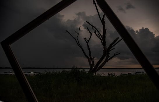 Chonburi, thailand - Oct 05, 2019 : Portrait of landscape of sunset sky with dry tree looking through at empty photo frame at Bang Pra reservoir at Chonburi Province.