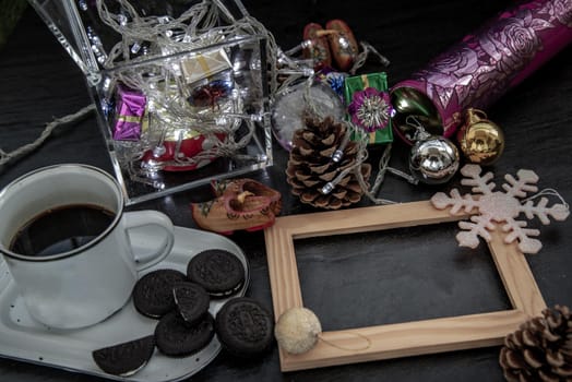 Cup of coffee with chocolate chip cookies and Christmas decoration with Empty wooden frame for work about design element.  Selective focus, Oblique view from the top, copy space