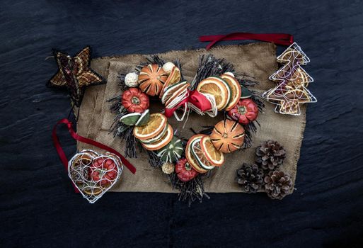 Christmas decoration. Twigs christmas tree, brown natural pine cones and variety of fruits on burlap fabric background. Top view.